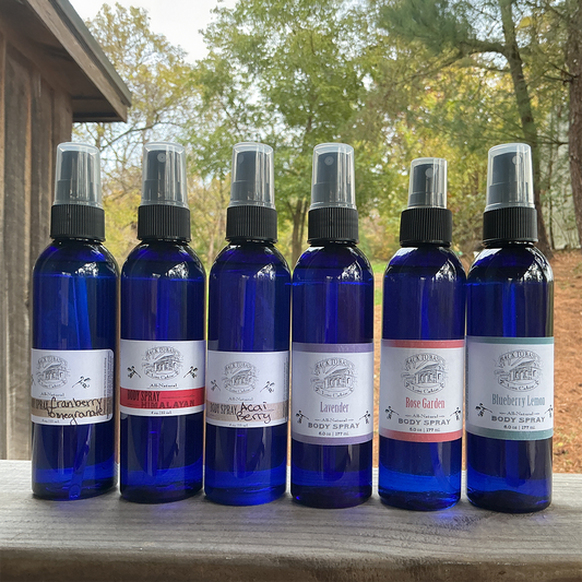 Six blue spray bottles with labels on a wooden surface outdoors.