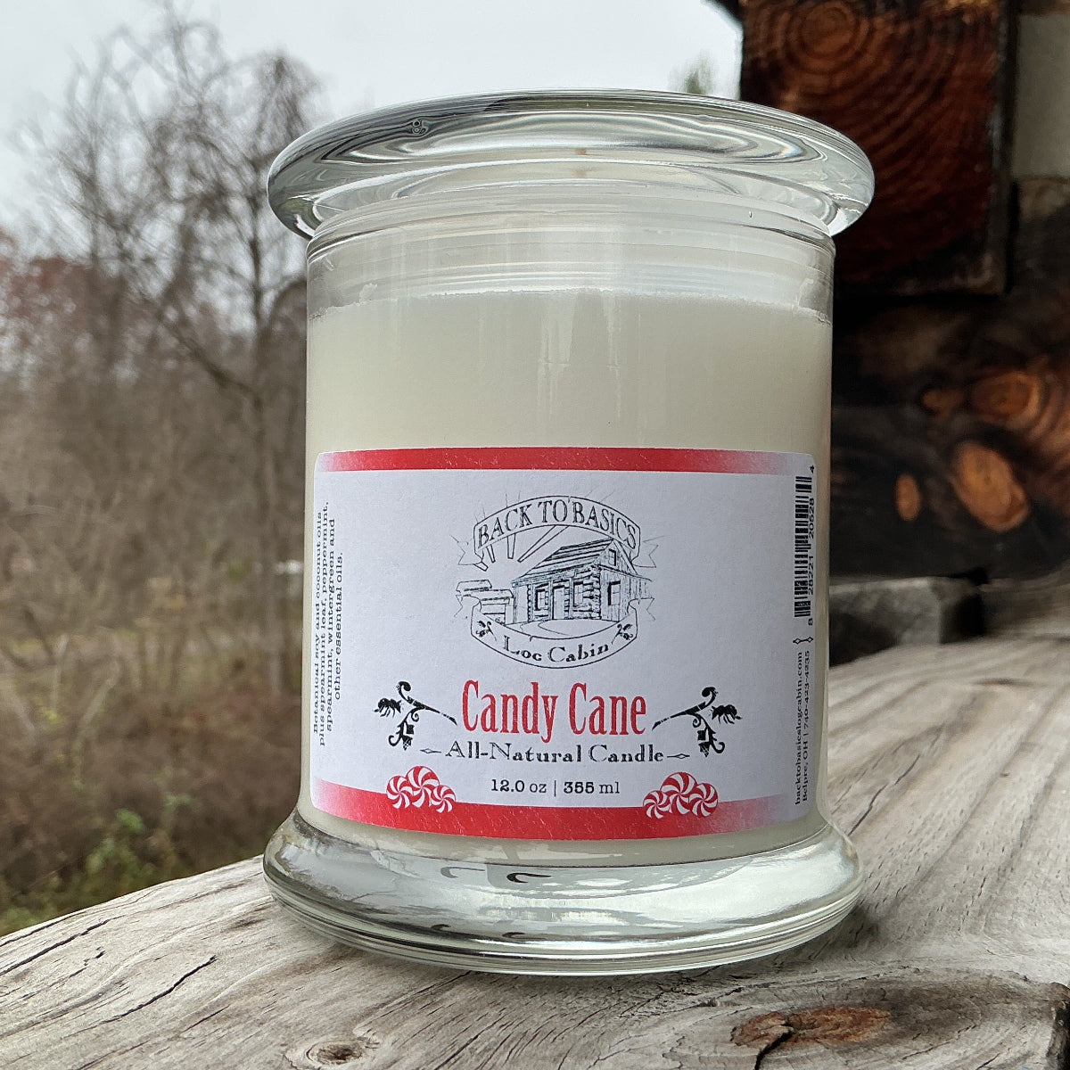 Candle in a glass jar with a label on a wooden surface outdoors