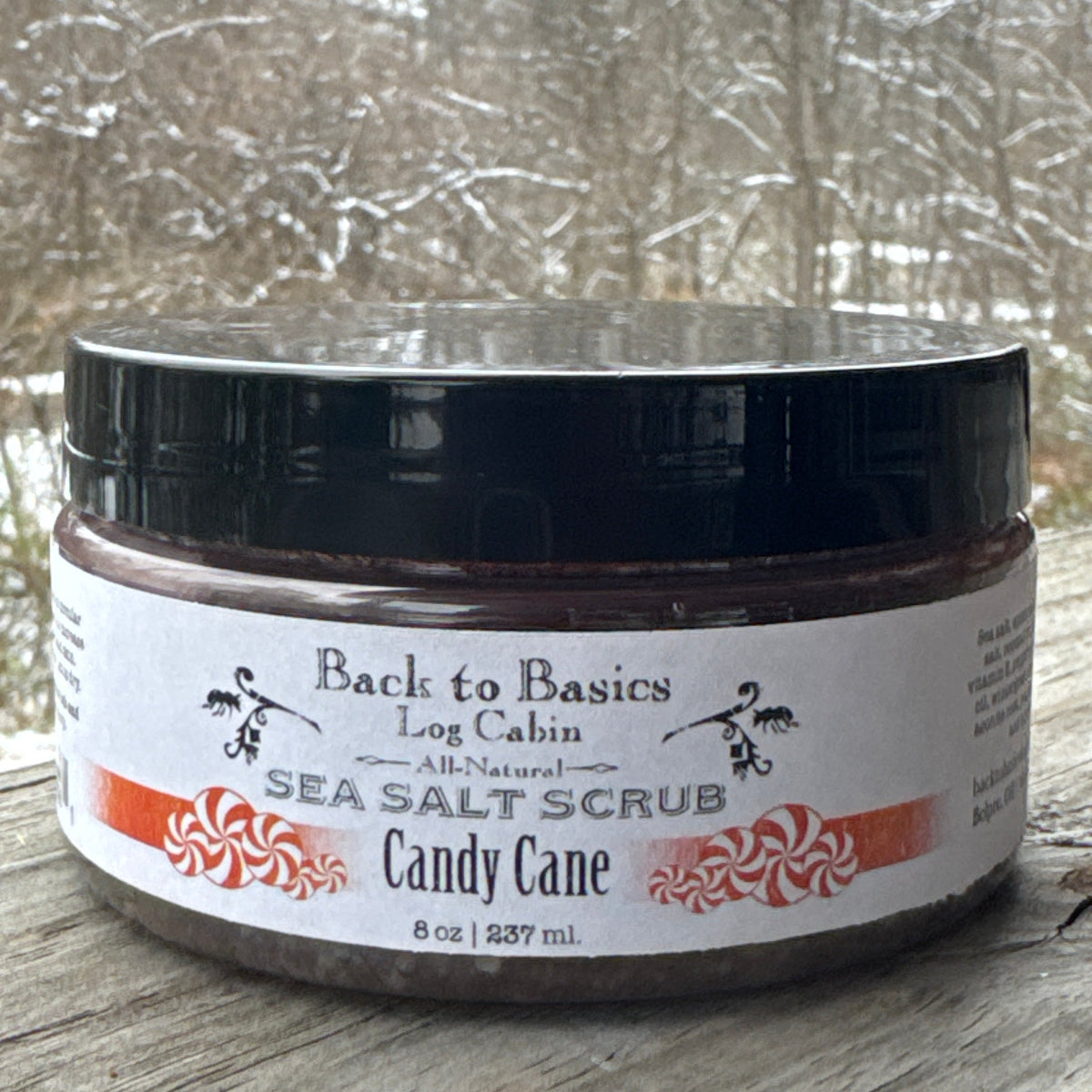 Jar of candy cane sea salt scrub with a blurred snowy background