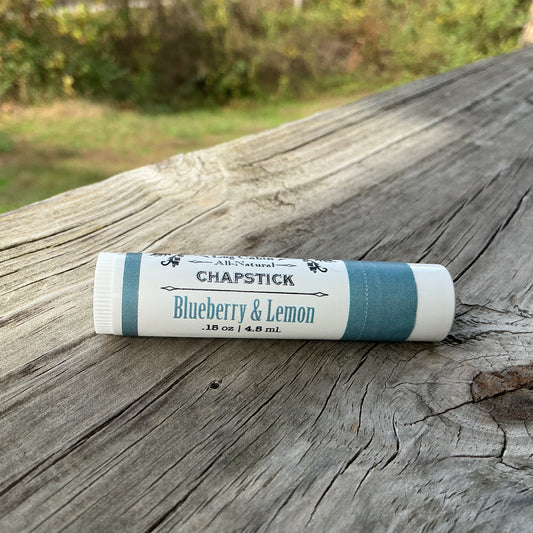Chapstick stick with 'Blueberry & Lemon' flavor on a wooden surface outdoors