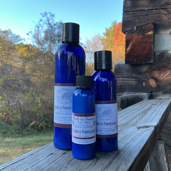 Three blue bottles with black caps on a wooden surface outdoors with trees in the background