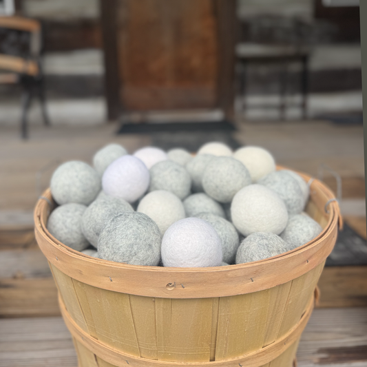 Basket filled with gray and white dryer balls on a wooden floor.