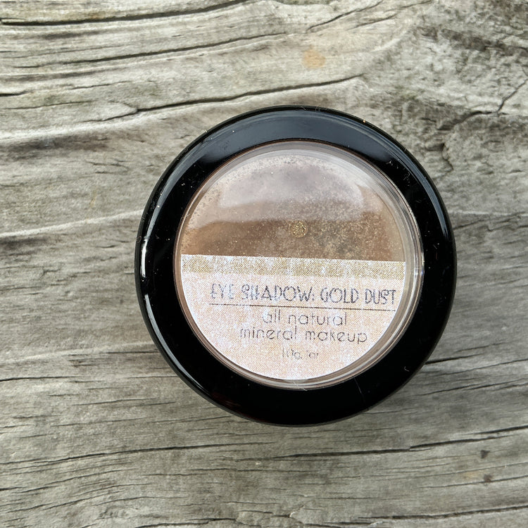 Makeup product labeled 'Eye Shadow Gold Dust' on a wooden surface