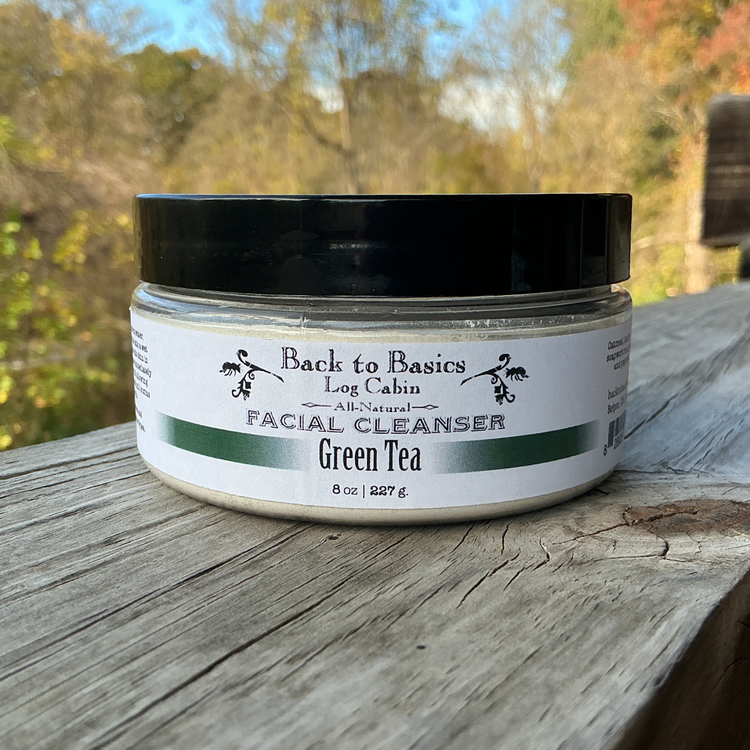 Facial cleanser jar labeled 'Back to Basics Log Cabin' on a wooden surface with a natural background