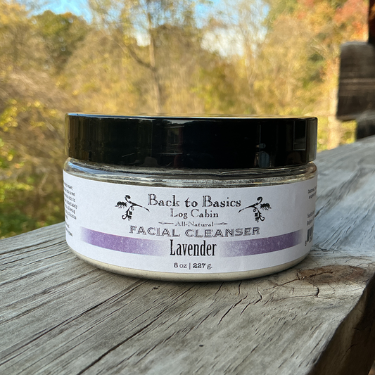 Facial cleanser jar labeled 'Back to Basics Log Cabin' on a wooden surface with a natural background