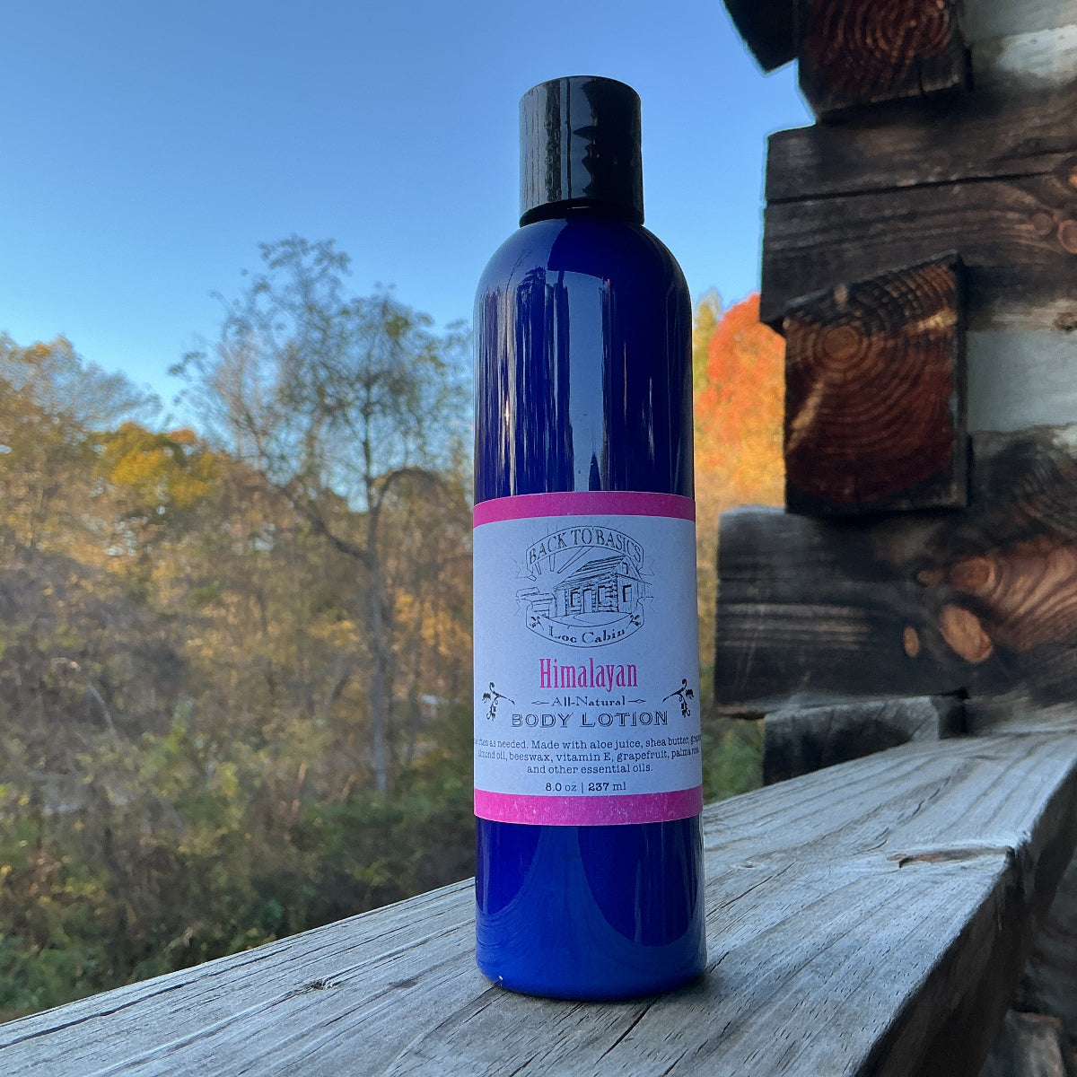 Blue bottle of Himalayan body lotion on a wooden surface with a scenic background