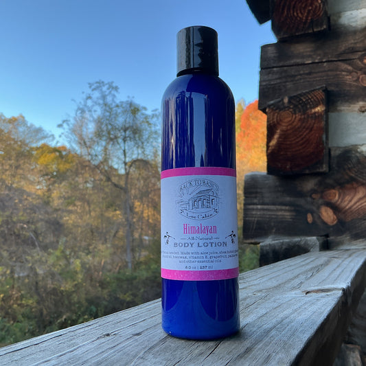 Blue bottle of Himalayan body lotion on a wooden surface with a scenic background