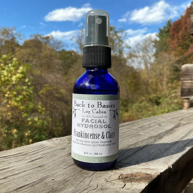 Bottle of 'Back to Basics Log Cabin' facial hydrosol on a wooden surface with a natural background