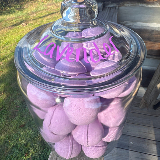 Clear glass jar filled with pink bath bombs on a wooden surface.