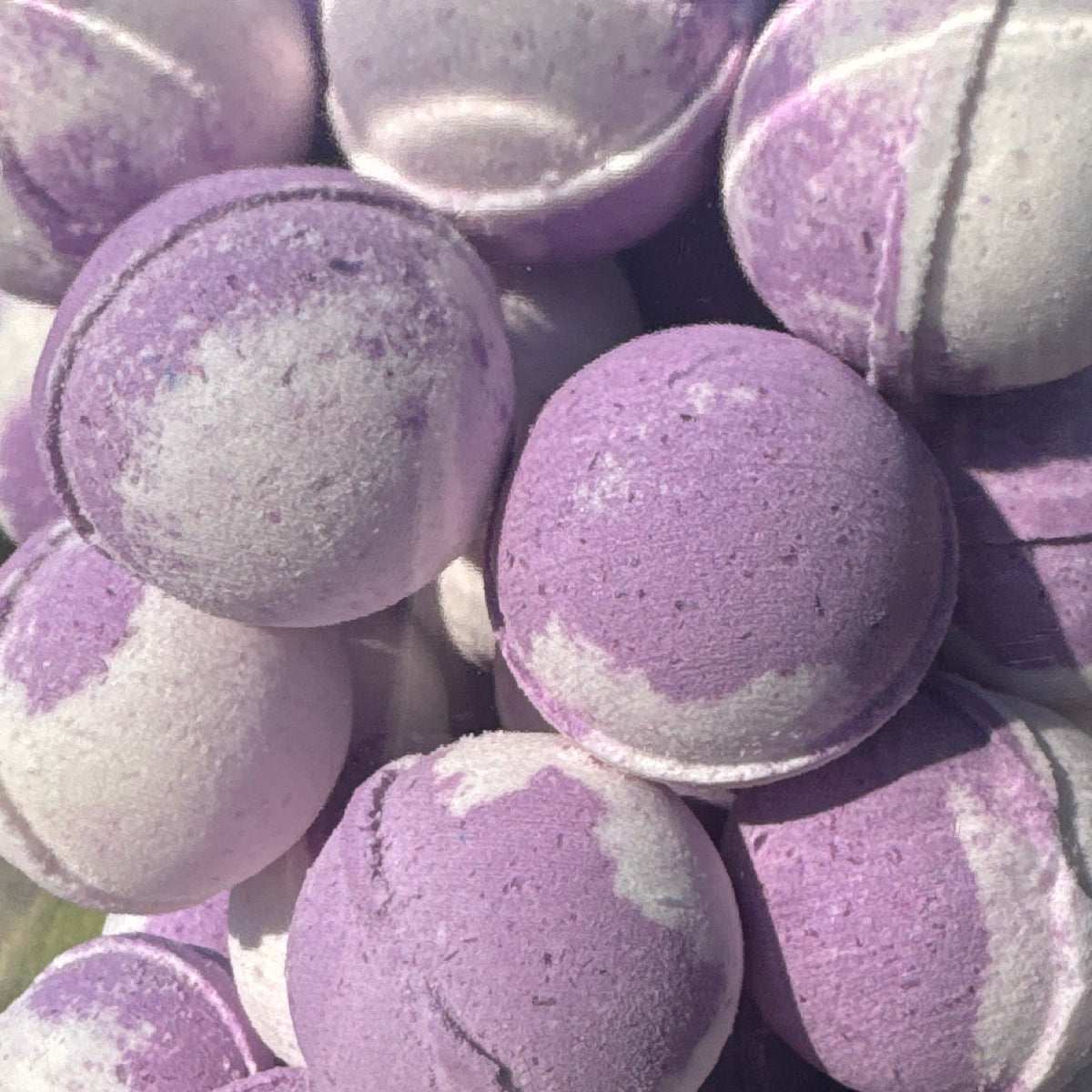 Clear jar filled with purple and white bath bombs on a reflective surface.