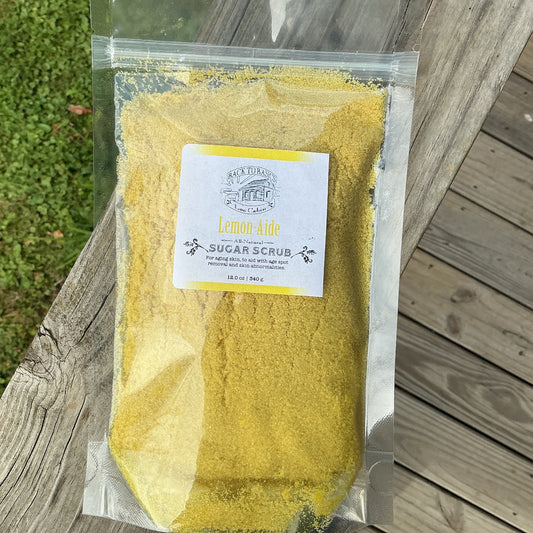 Yellow sugar scrub in a clear plastic bag with a label on a wooden surface.