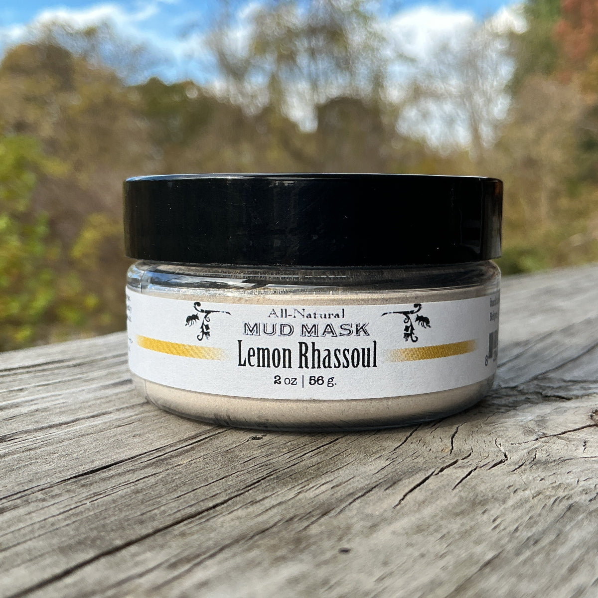 Jar of lemon rhassoul mud mask on a wooden surface with a natural background