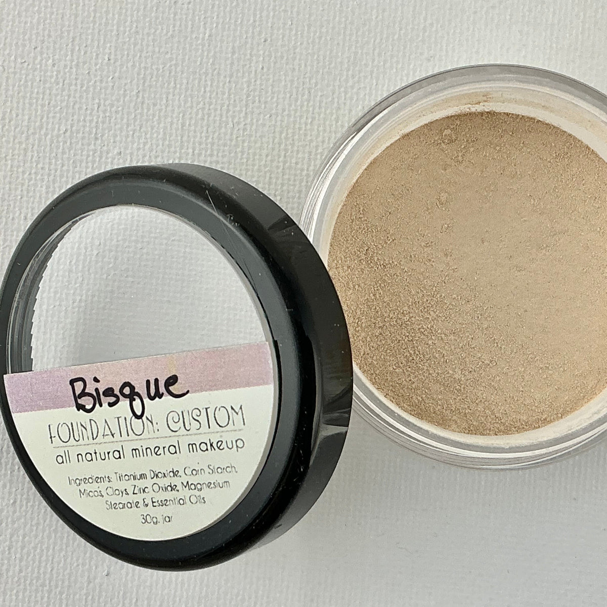 Open container of Bisque Foundation Custom mineral makeup on a light gray background