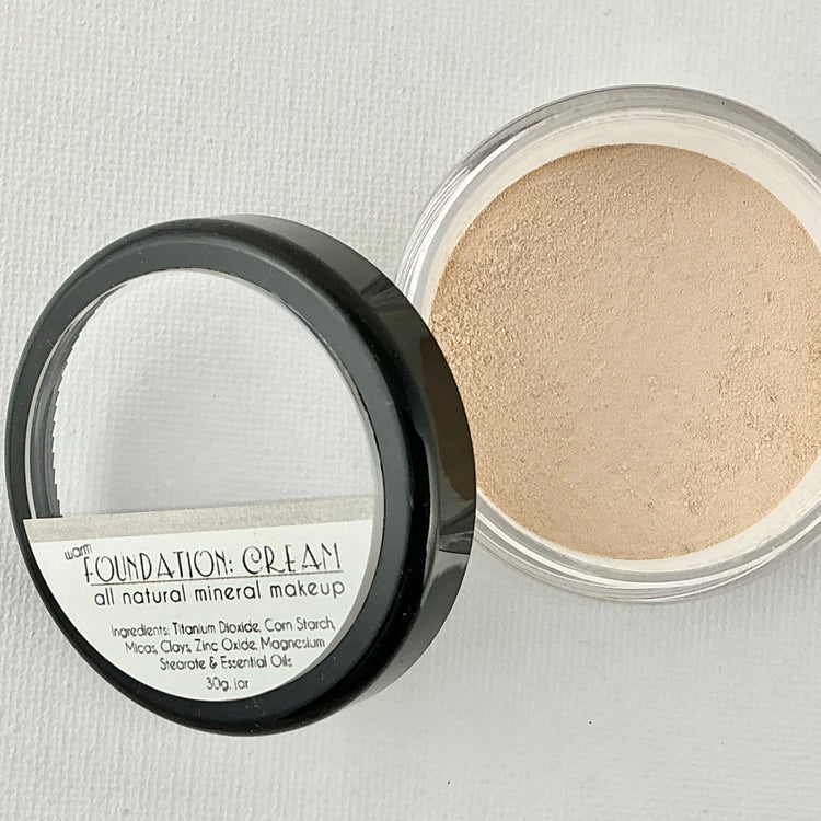 Open container of foundation cream with visible label on a light gray background