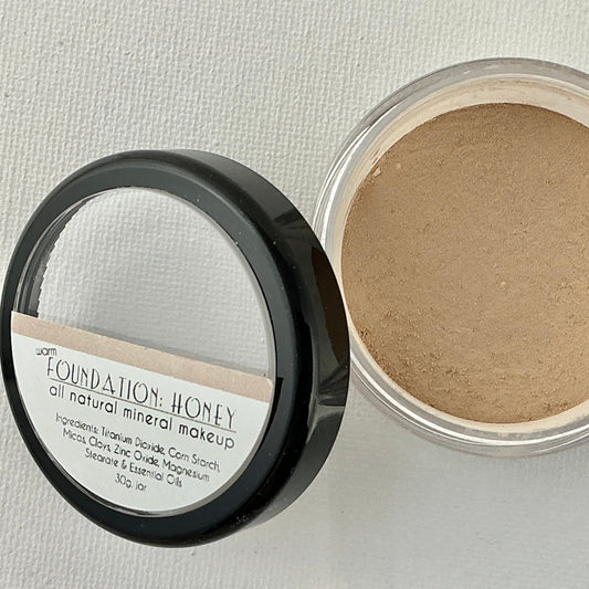 Open container of foundation powder with visible label on a light gray background