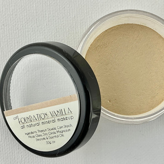 Open container of foundation powder with visible label on a light gray background