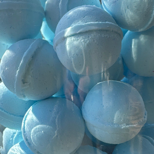 Clear glass jar filled with light blue bath bombs outdoors.