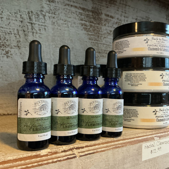 Bottles and jars with labels on a wooden shelf against a textured wall.