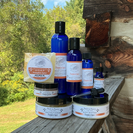 A collection of natural haircare products from The Wood Cuts Apothecary, including blue bottles, a jar of shampoo, and a bar of soap, arranged on a rustic wooden porch railing with a green outdoor background.