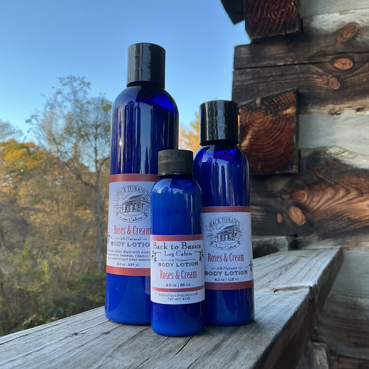 Three blue bottles of 'Romeo & Cream' body lotion on a wooden surface with a natural background.