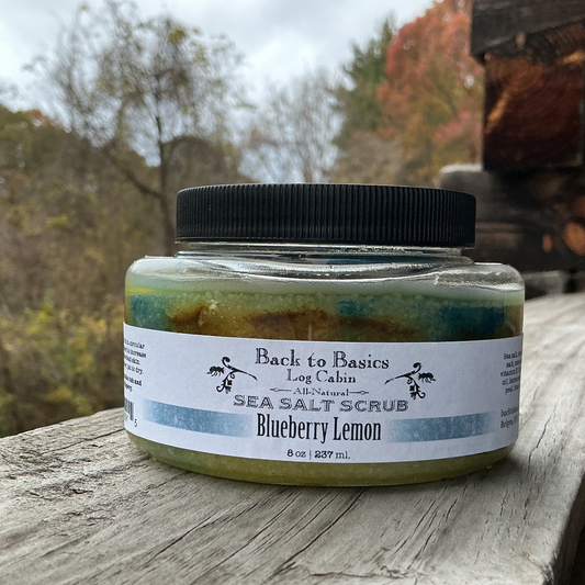 Jar of sea salt scrub labeled 'Back to Basics Log Cabin' on a wooden surface with a natural background