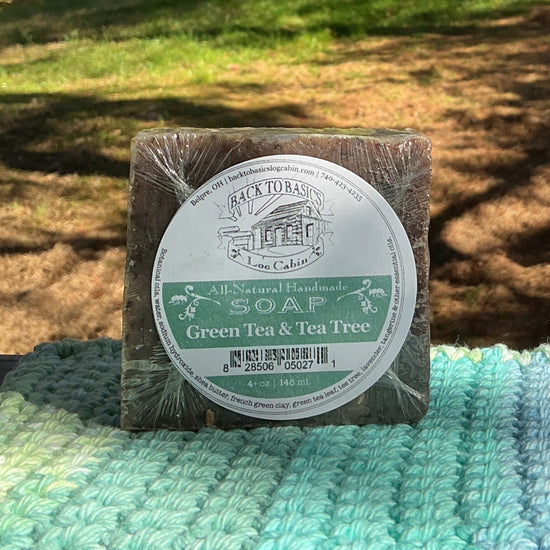 Bar of soap on a green and blue textured surface with a natural outdoor background
