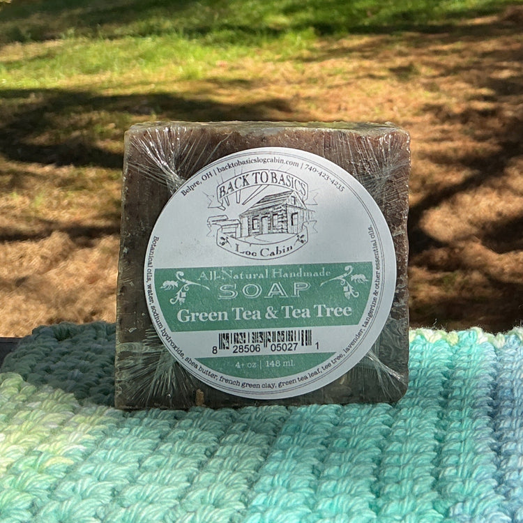 Bar of soap on a green and blue textured surface with a natural outdoor background