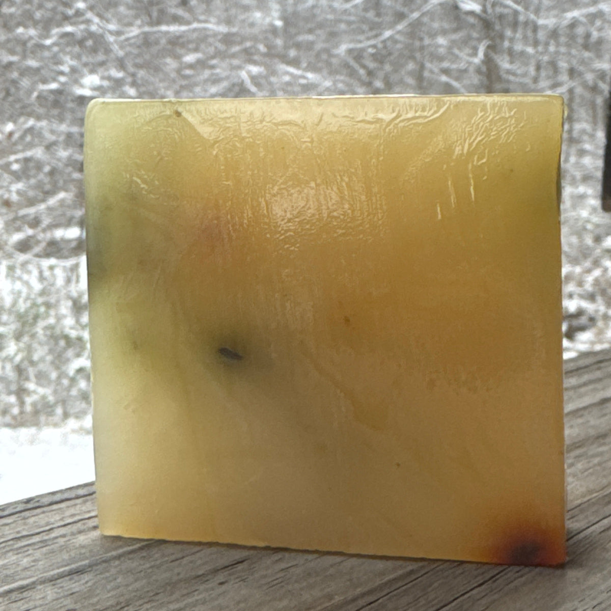 Square piece of amber-colored soap on a textured surface