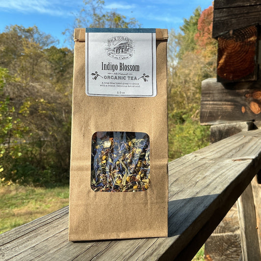 Brown package of Indigo Blossom Organic Tea on a wooden surface with a natural background