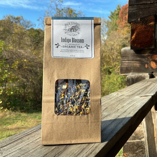 Brown package of Indigo Blossom Organic Tea on a wooden surface with a natural background