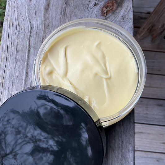 Open container of cream on a wooden surface with grass in the background